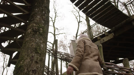 Female-looking-up-at-treehouse-in-forest