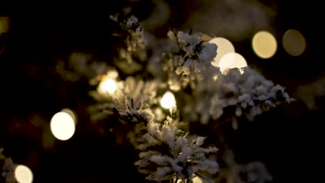 Christmas-snowed-artificial-tree-branches-with-lights,-Close-up-moving-shot