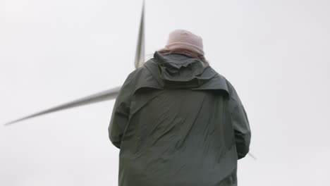 Female-walks-with-wind-turbine-in-background