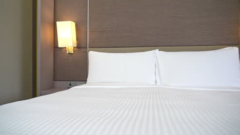Slow-pan-across-a-hotel-bed-made-up-with-white-sheets-and-pillows