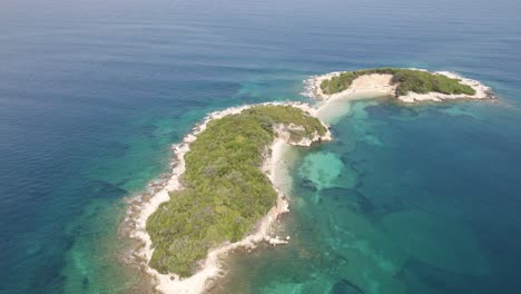 Drone-rotating-over-a-beautiful-island-in-the-Ionian-Sea,-Albania-on-a-sunny-day