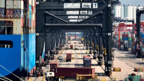 Ein-Lkw-Mit-Einem-Container-Biegt-Beim-Beladen-Des-Schiffsriesen-Im-Hafen-Von-Hongkong-Unter-Den-Containerkränen-In-Eine-Spur-Ein