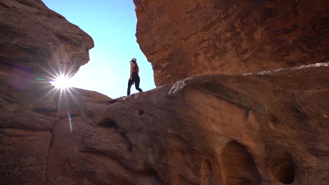 Mujer-Joven-Caminando-Sobre-La-Roca-De-Arenisca-En-El-Impresionante-Paisaje-Del-Parque-Del-Monumento-Nacional-De-Colorado-Usa,-ángulo-Bajo