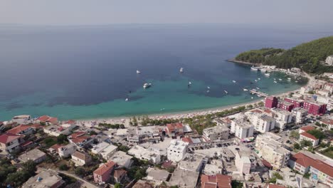 Drone-view-of-the-beautiful-quiet-beach-town-of-Himare,-Albania-with-a-stunning-view-of-the-Ionian-Sea