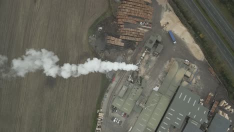 Top-View-Of-Woodworking-Plant-With-Chimney-Smoke-And-Stack-Of-Woods-In-Portlaoise,-County-Laois,-Ireland