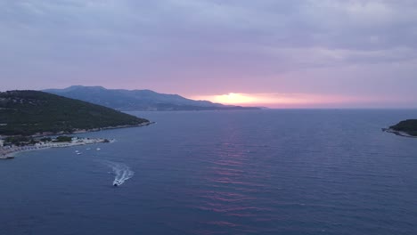 Aerial-View-Of-Boat-Travelling-Over-Ionian-Sea-With-Orange-Sunset-In-Horizon