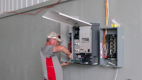 Technician-using-a-drill-and-level-to-hang-the-transfer-station-for-a-Generac-solar-home-backup-power-system