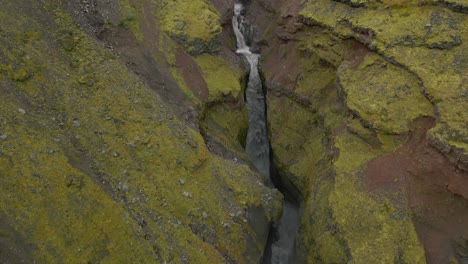 Eine-Geschichtete-Felsschlucht-Mit-Wasser,-Das-Ein-Enges-Tal-Zwischen-Einem-Berg-Hinunterfließt,-Mit-Steilen-Felswänden-Und-Einem-Bach,-Der-Durch-Sie-Fließt-Und-Einen-Wasserfall-Bildet