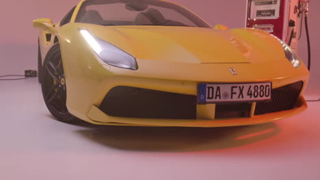 yellow-Ferrari-in-the-studio-next-to-a-petrol-pump,-camera-moves-towards-the-hood