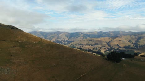 Drone-reveal-of-dramatic-huge-valley-in-New-Zealand-surrounded-by-rolling-hills-of-green-in-secluded-Akaroa-South-Island