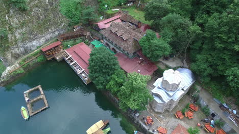 Aerial-shot-of-resort-near-the-pond-with-boat-sailing-in-the-pond