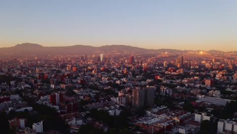 Wide,-forward-moving-establishing-aerial-drone-shot-of-Mexico-City-at-sunset