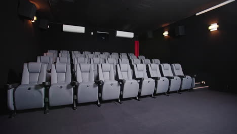 Sitzreihen-Mit-Blick-Auf-Den-Bildschirm-In-Einem-Schwach-Beleuchteten-Kleinen-Lokalen-Kino,-4k