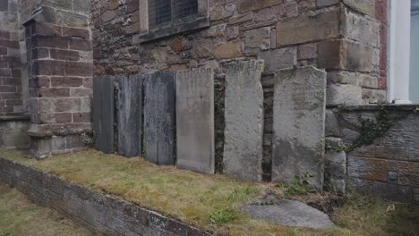 A-line-of-old-gravestones-against-the-side-of-the-church