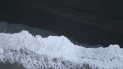 Waves-crash-onto-a-surf-beach-with-black-sand