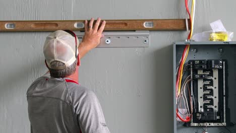Technician-using-a-level-and-drill-to-finalize-placement-the-support-bracket-for-the-power-system-control-station
