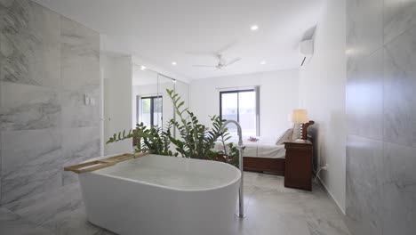 Luxuriöses,-Modernes,-Zeitgemäßes-Badezimmer-Und-Schlafzimmer,-Weißer-Marmorfliesenboden,-Freistehende-Badewanne,-Zimmerpflanzen,-Bodenlange-Spiegel,-Große-Fenster