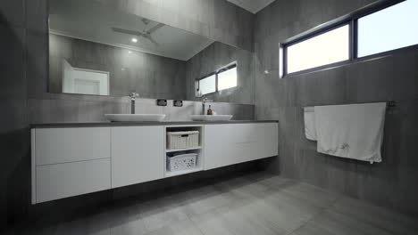 Luxurious-modern-bathroom-with-sleek-grey-tiles,-white-bath-and-white-fixtures-in-a-contemporary-residential-home