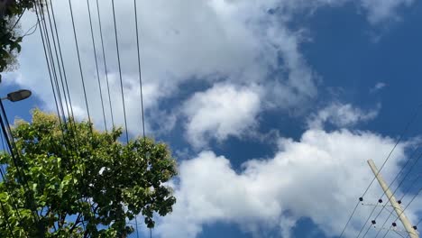 Cielo-Azul-Con-Nubes-Esponjosas-Blancas-Y-Cables-Eléctricos