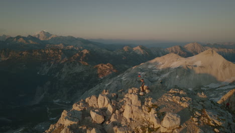 Drone-shot-in-early-morning-of-top-of-mountain-Krn-where-a-hiker-is-standing-with-a-slovenian-flag-which-waves-in-the-wind