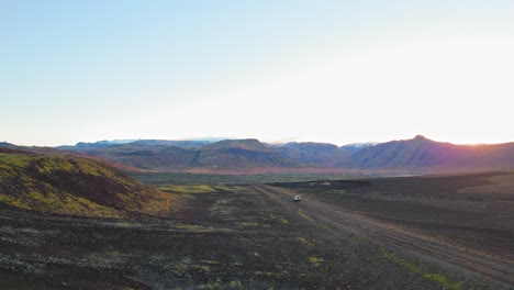 Luftaufnahme-Eines-Weißen-Land-Rovers,-Der-Auf-Einer-Isländischen-Straße-Mit-Einem-Atemberaubenden-Berghintergrund-Fährt