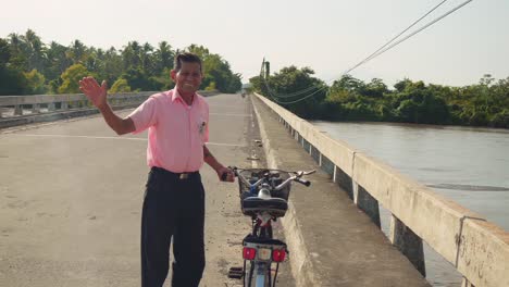 Breite-Aufnahme-Eines-Guatemaltekischen-Mannes,-Der-Fahrrad-Hält-Und-In-Die-Kamera-Lächelt-Und-Bei-Sonnenuntergang-Auf-Der-Straße-Steht