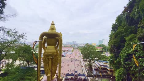 High-angle-shot-from-top-of-stairways-of-back-side-of-a-golden-statue-of-Hindu-God-Murugan-in-front-of-Subramanya-temple-along-Batu-Caves,-Malaysia