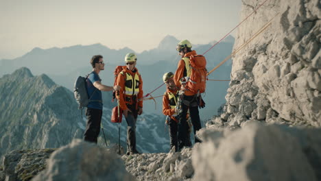 Hiker-meets-three-rescueclimbers-in-orange-gears-and-casually-talks-with-them
