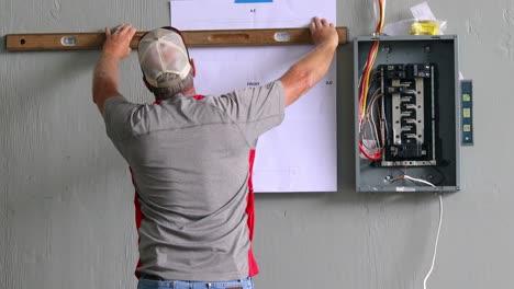 Technician-using-a-level-to-find-placement-of-control-station-in-relationship-to-electrical-panel