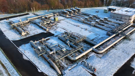 Gas-pipeline-operational-plant-at-Wallbach-Switzerland-in-snow,-drone-down-pedestal-tilting-shot