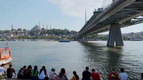 Toursit-and-local-sitting-under-The-Bosphorus-Bridge-known-officially-as-the-15-July-Martyrs-Bridge,-istanbul,-Tureky-on-20