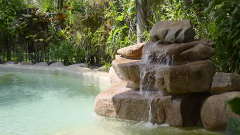 Fließendes-Wasser-In-über-Felsen-In-Außenpool-Felsenbrunnen-Tropischen-Garten