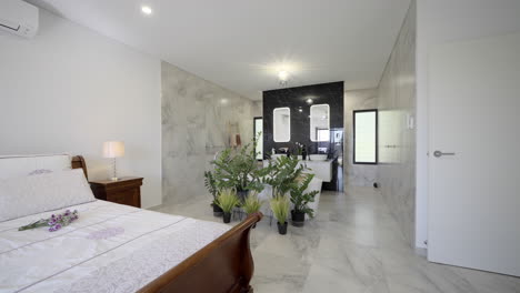 Luxuriöses,-Modernes,-Zeitgenössisches-Schlafzimmer-Badezimmer-Weißer-Marmorfliesenboden-Freistehende-Badewanne-Zimmerpflanze-LED-Spiegel-Schwarze-Feature-Wand-Fenster-Weißer-Waschtisch-Waschbecken-Handtuchhalter
