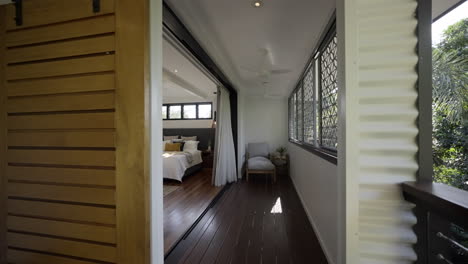Barn-door,-outdoor-wooden-deck-into-contemporary-modern-styled-bedroom-with-wooden-floor-boards
