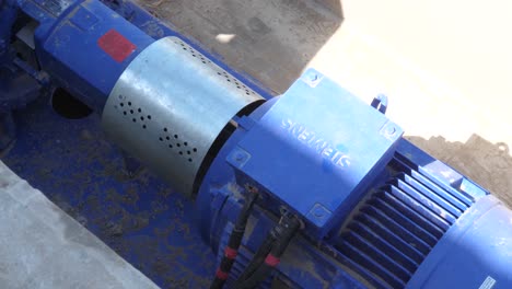 Close-shot-of-a-blue-diesel-pump-used-for-drawing-water-from-a-nearby-water-body-to-irrigate-farmland-on-a-sunny-day
