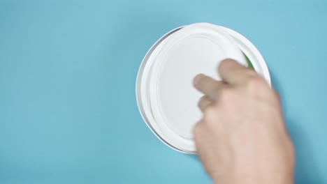 Close-shot-of-a-hand-opening-can-with-green-paint