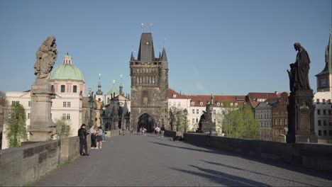 People-walking-Charles-Bridge-or-Karluv-most-in-Prague-with-Old-Town-Tower-in-background
