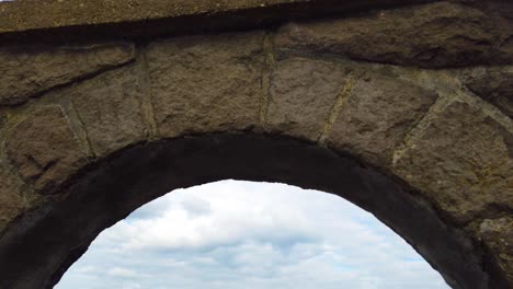 4K-Nice-tilt-down-to-reveal-view-of-the-Columbia-River-through-an-archway-with-mostly-cloudy-sky