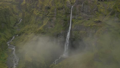 flying-through-clouds-to-reveal-a-large-majestic-waterfall-in-the-distance