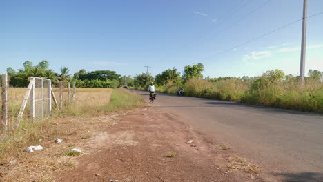 A-solo-Asian-woman-long-distance-cyclist-and-backpacker-dressed-in-athletic-clothes-riding-through-the-road-of-Udon-Thani-on-her-foldable-bicycle-on-the-left-corner-of-the-road,-Thailand