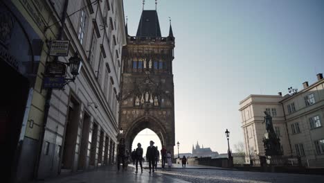 People-or-tourists-walking-under-Old-Town-Bridge-Tower-in-Prague,-low-wide-angle-view,-Czech-Republic