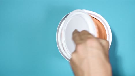 Close-shot-of-a-hand-opening-can-with-peach-pink-paint