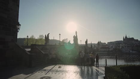 Charles-Bridge-or-Karluv-most-in-Prague-with-group-of-people-and-sun-rays-or-beams,-morning-view
