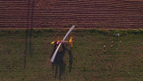 Gyrocopter-take-off-with-white-blades-spinning-at-full-speed,-top-down