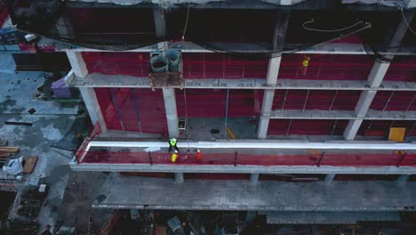 Aerial-view-of-a-crane-lifting-buckets-of-liquid-to-a-construction-site---tilt,-drone-shot