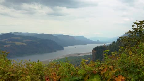 HD-Boom-up-with-autumn-colored-hedges-in-foreground-and-the-Vista-House-on-a-cliff-in-the-distance-overlooking-the-Columbia-River-with-mostly-cloudy-sky-take-one