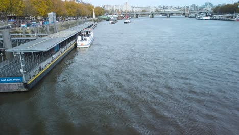Hochwinkelaufnahme-über-Der-Themse-Mit-Motorbooten,-Die-Tagsüber-Am-Flussufer-Mit-Der-Millennium-Fußbrücke-In-London,-Großbritannien,-Angedockt-Sind