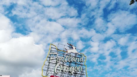 4K-Tilt-down-from-a-tree-frame-right-with-partly-cloudy-sky-to-wide-shot-of-Portland-Oregon-Old-Town-sign-center-frame
