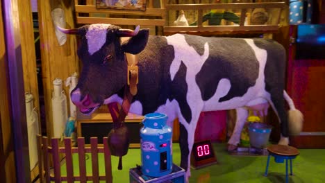 Pan-shot-revolving-around-an-automated-holstein-friesian-cows-moving-head-in-an-amusement-park-in-London,-UK-at-night-time