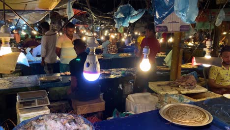 Vendedores-Que-Venden-Pescado-Fresco-Cubierto-De-Hielo-En-Un-Mercado-De-Polvo-Solar-Interior,-Bangladesh
